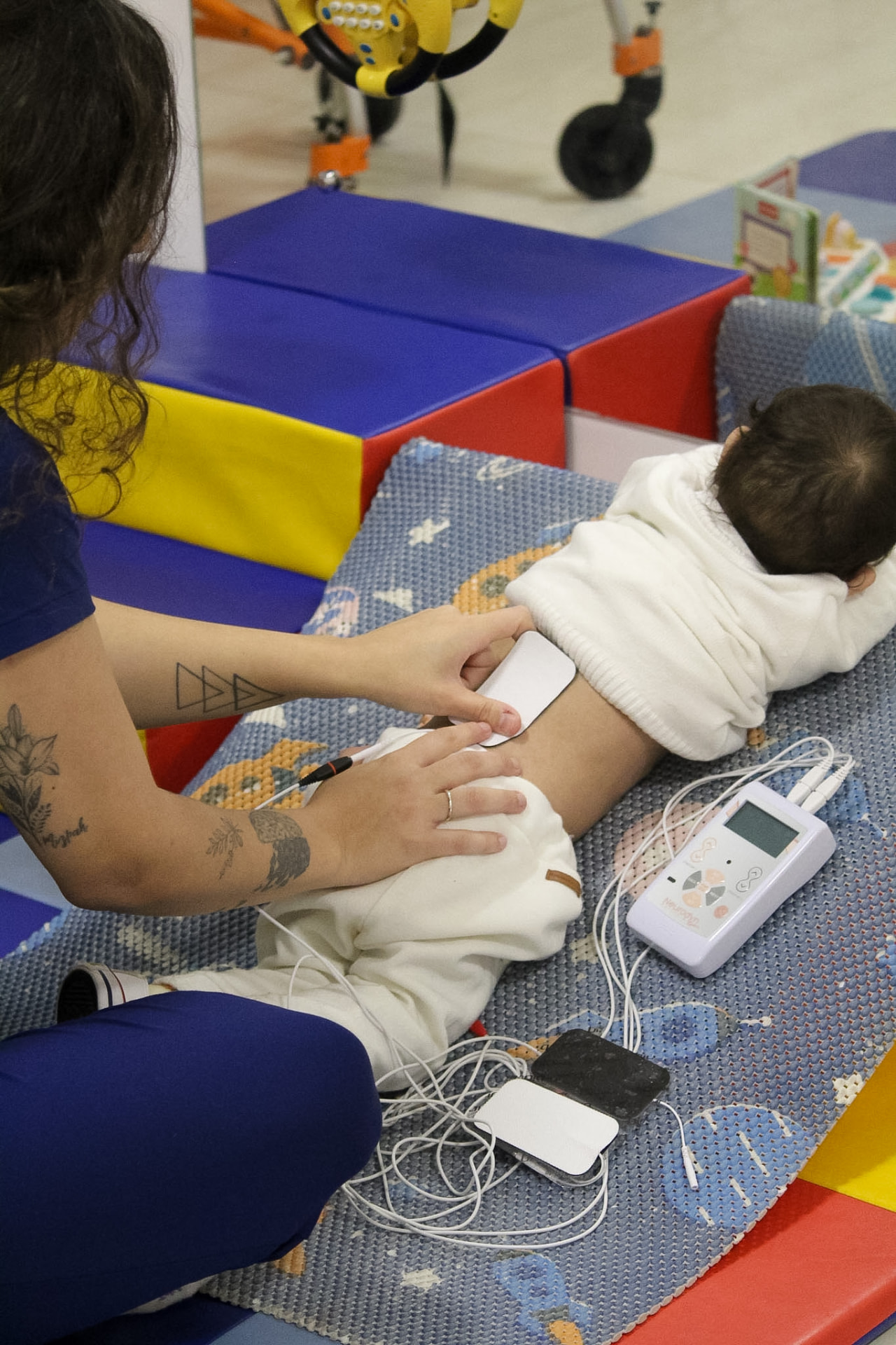 Fisioterapeuta utilizando recurso eletroterapêutico durante atendimento de bebê